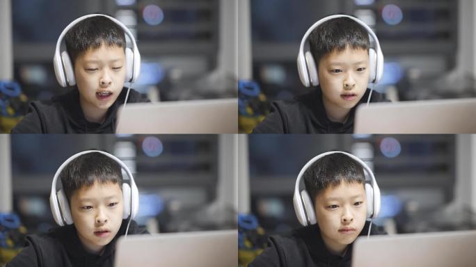 男孩子带着耳机使用笔记本电脑学习