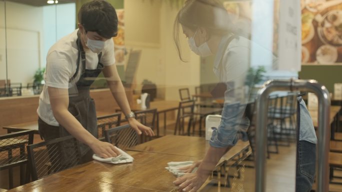 服务员在餐厅擦桌子时戴着防护口罩