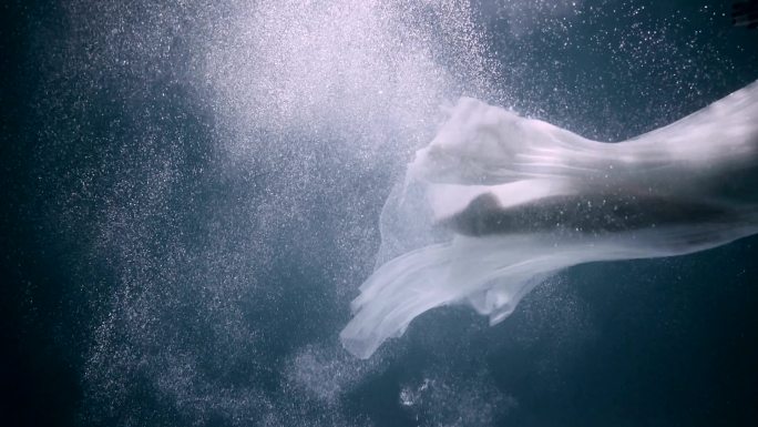 穿着白色优雅连衣裙在水下游泳的美女