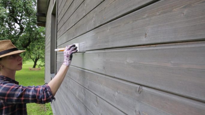 女工用漆刷粉刷木屋外墙