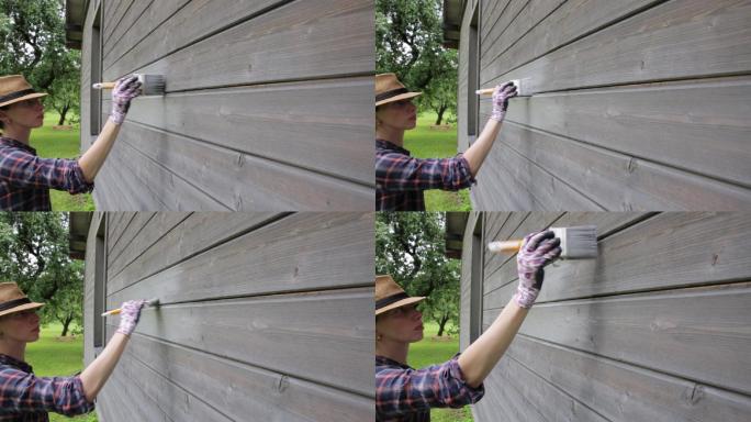 女工用漆刷粉刷木屋外墙