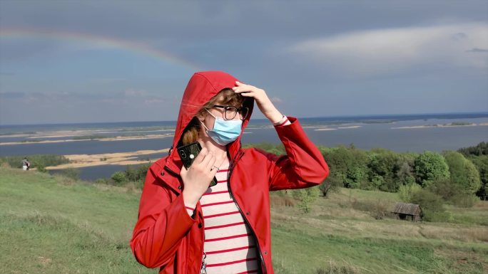 身穿红色夹克的妇女站在彩虹的天空背景下