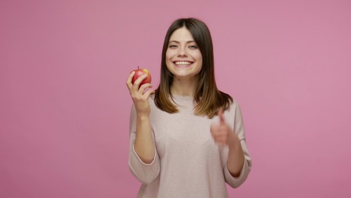 女性享受新鲜红苹果的味道竖起大拇指