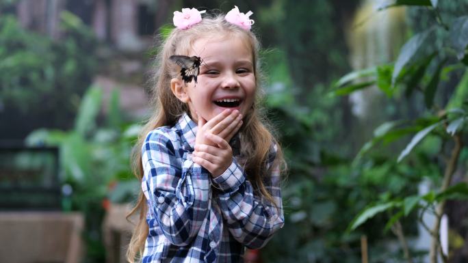 美丽的女孩笑得很开心。她脸上有一只蝴蝶。