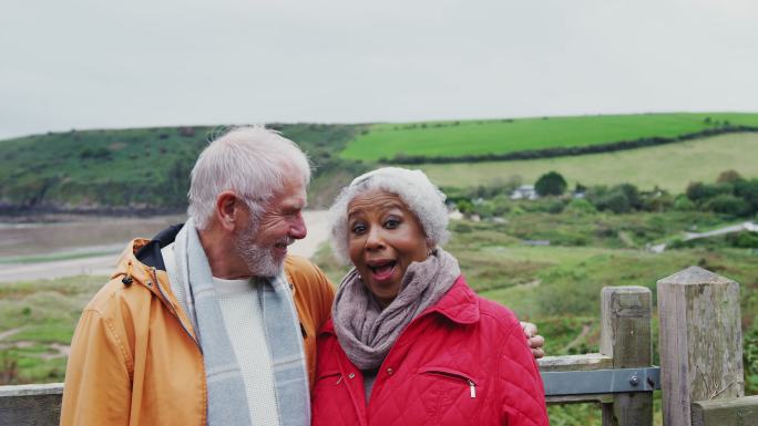 一对微笑的老年夫妇沿着海岸小道散步