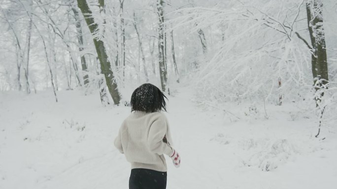 黑发女孩在雪林中欢快地奔跑