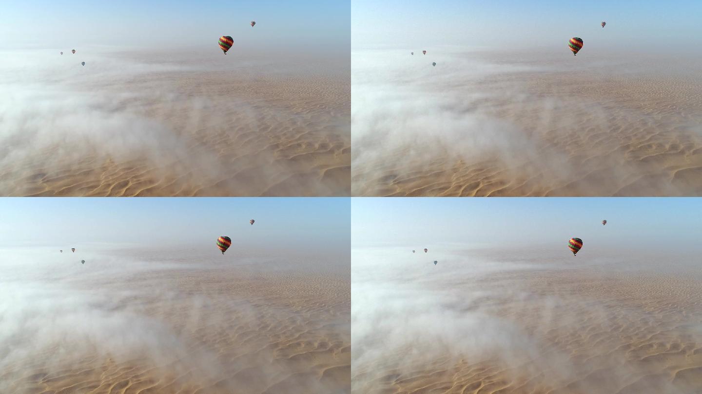 沙漠上的热气球在云层中飞行的鸟瞰图。
