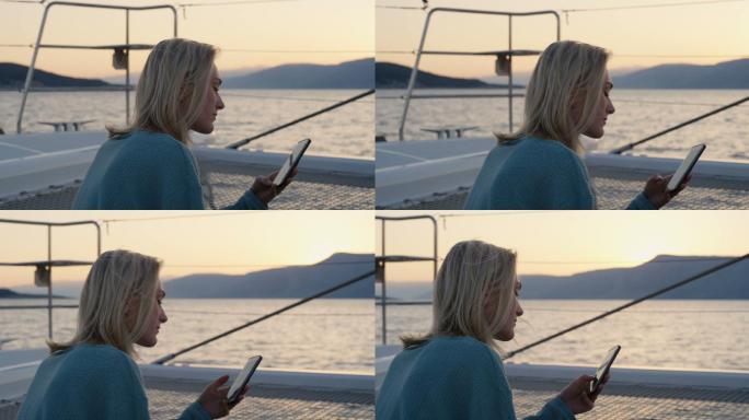 年轻女性在游艇上使用智能手机。