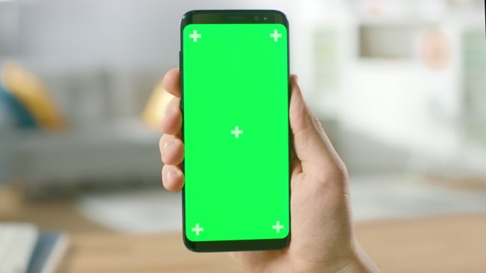 一名男子手持绿色屏幕智能手机