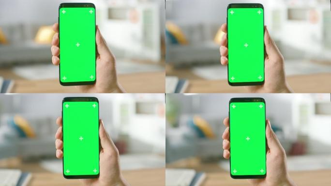一名男子手持绿色屏幕智能手机
