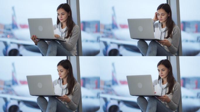 在机场窗口附近用笔记本电脑工作的女人