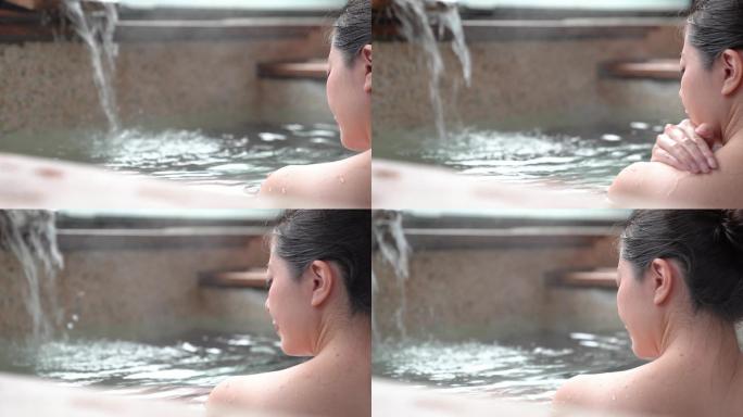 女孩泡在温泉里，用手把水舀到身上的后视图