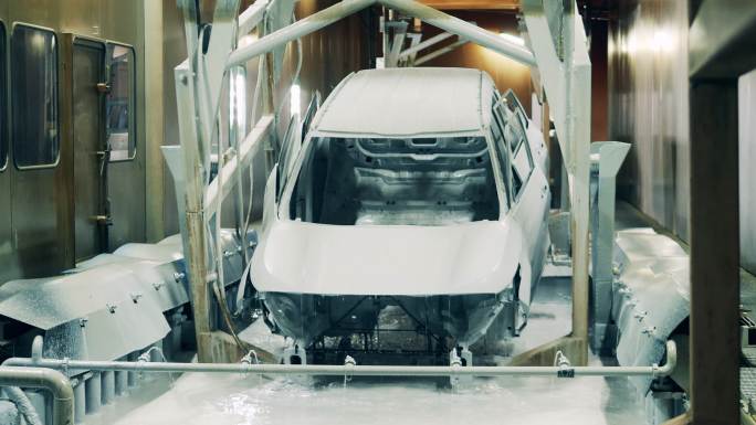 在一家汽车制造厂，汽车被浸泡在溶液中