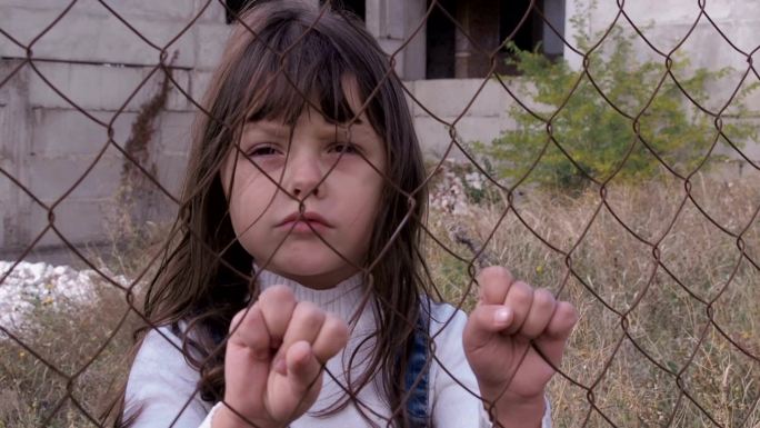一个无家可归的孩子躲在铁栅栏后面。