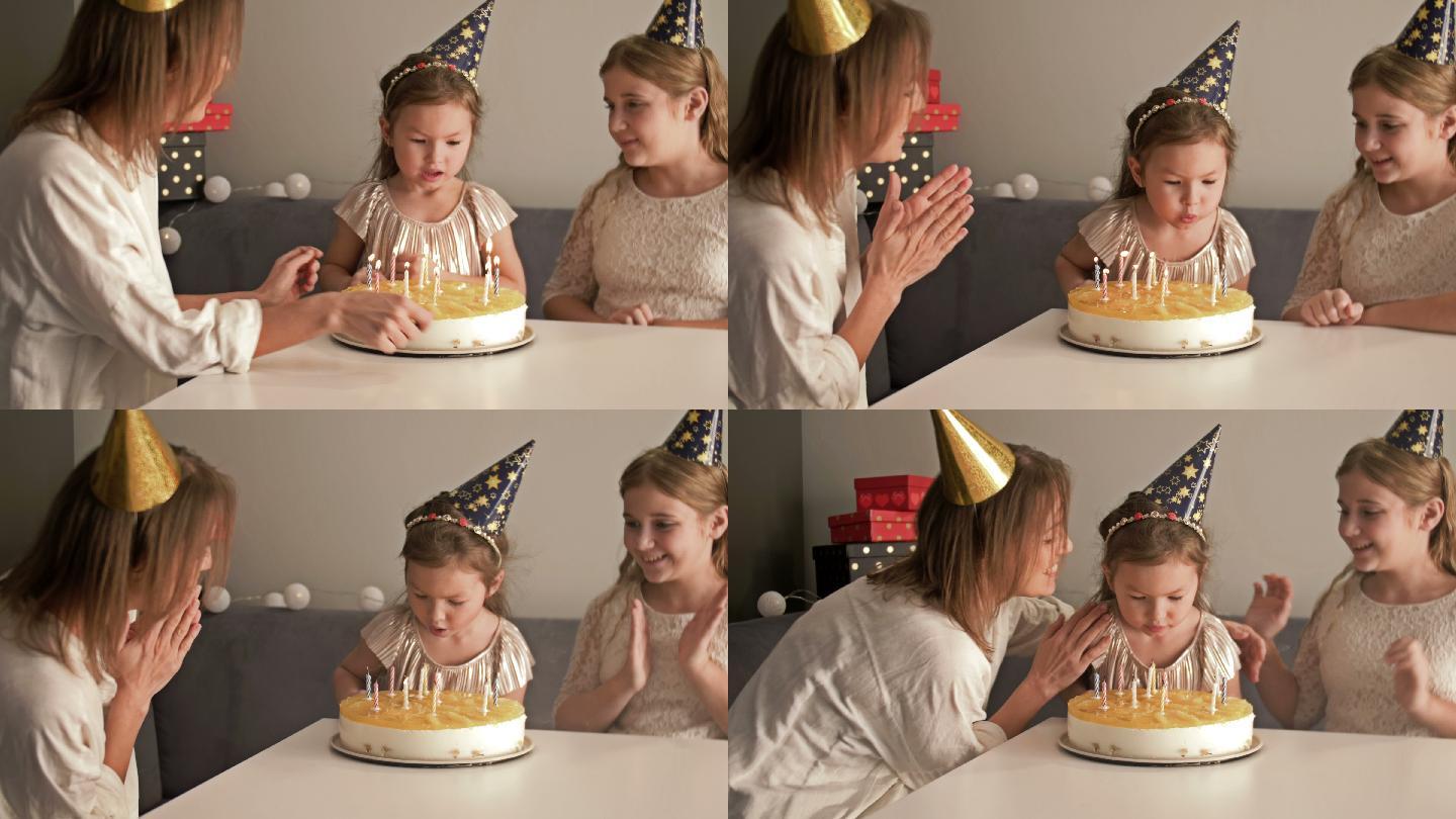 微笑的母亲和女儿们在生日蛋糕上吹灭蜡烛