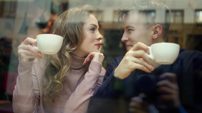 年轻幸福的浪漫情侣坐在咖啡馆的窗前