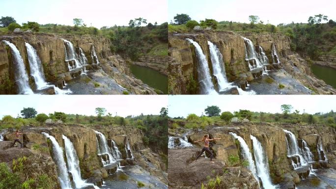 在瀑布边岩石上的金发女孩正在做瑜伽