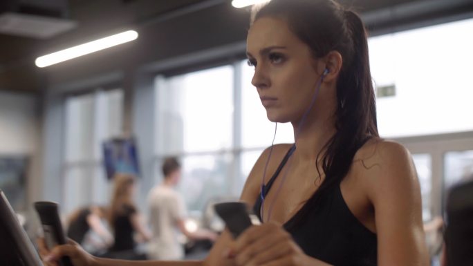 戴着耳机在健身房锻炼的女人