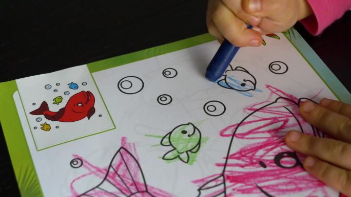 一个三岁的孩子用彩色蜡笔涂色