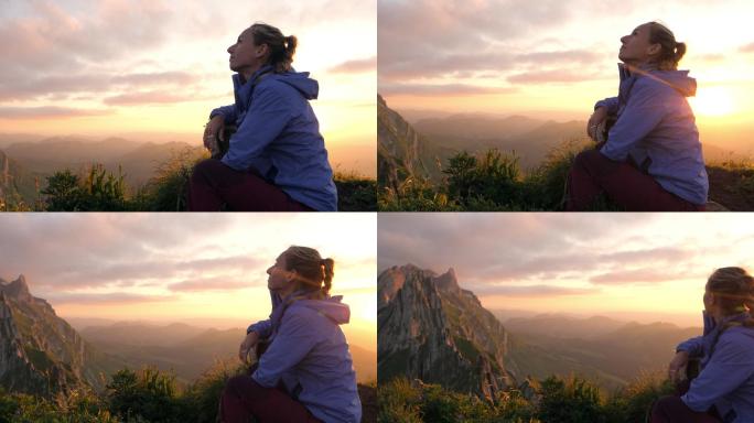 日出时分，坐在山顶上的女性欣赏高山风光。