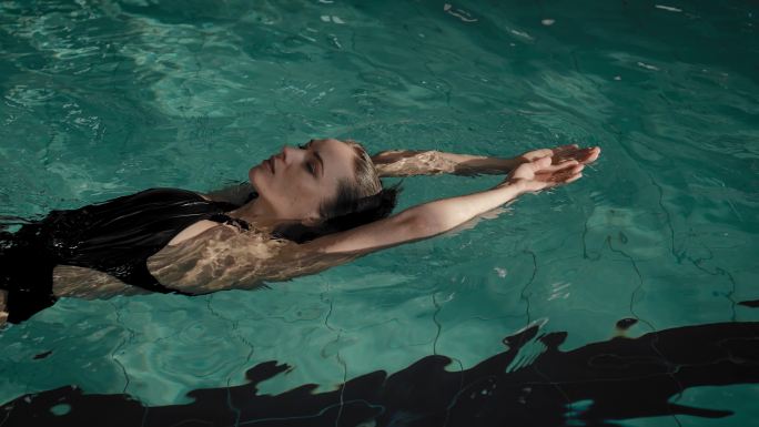 游泳池里的女人惬意舒适悠闲享受漂浮放空