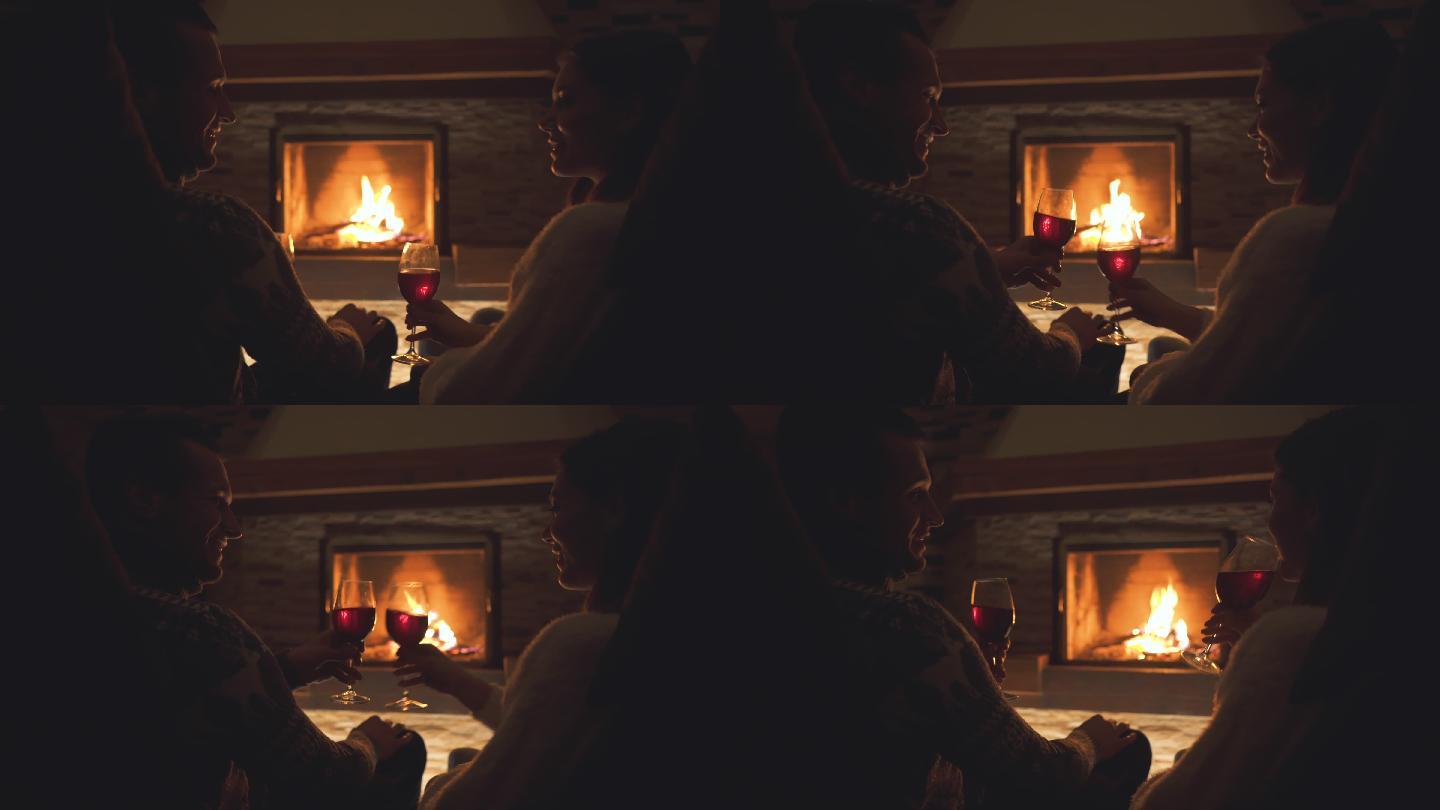 幸福的夫妇坐在壁炉旁喝酒
