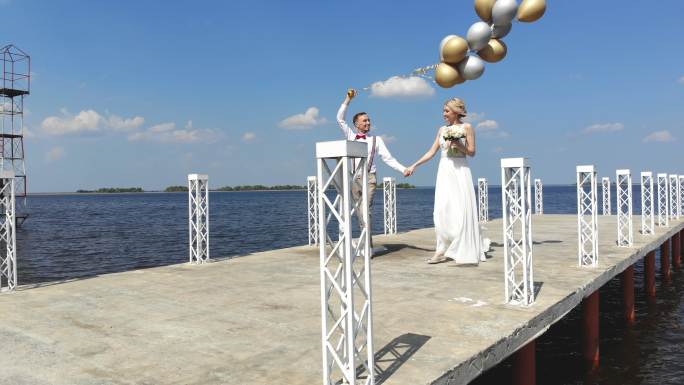 年轻美丽的新婚夫妇走在美丽的码头上
