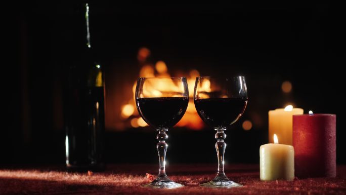 两杯红酒和一个瓶子放在壁炉的背景下