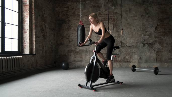 穿着运动服的女人在健身房骑着自行车锻炼