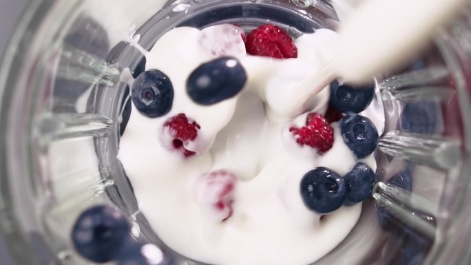 带酸奶的浆果落入搅拌器