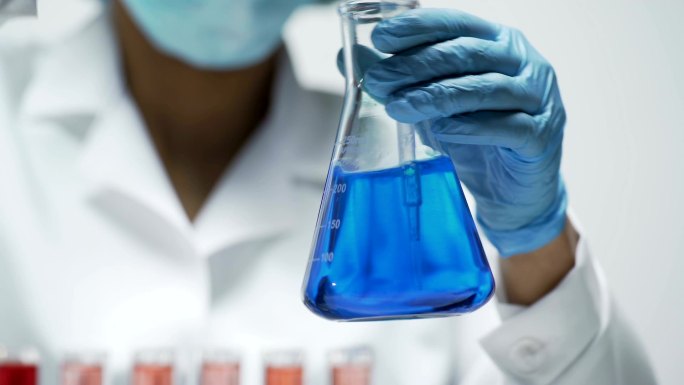 研究人员在锥形瓶中搅拌亮蓝色液体