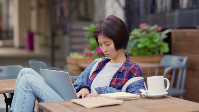 女性坐在笔记本电脑上工作或学习，若有所思