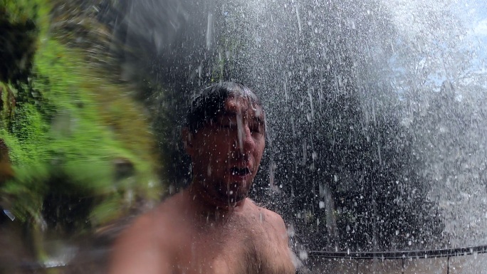 一名男子正在拍摄进入瀑布的自拍视频。