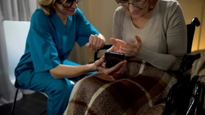 护士向老年女性展示如何使用手机
