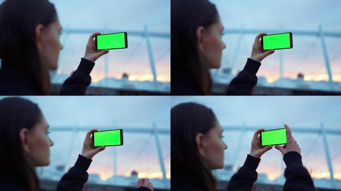 用绿色屏幕手机拍照的女孩。