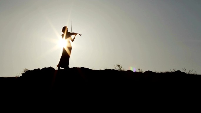 小提琴家剪影演奏夕阳山顶拉琴