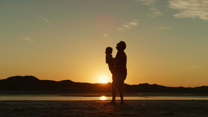 父亲和儿子在海滩上向对方奔跑的剪影