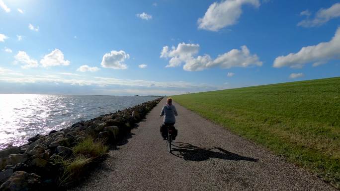 一名女子骑着自行车穿过海边的公路