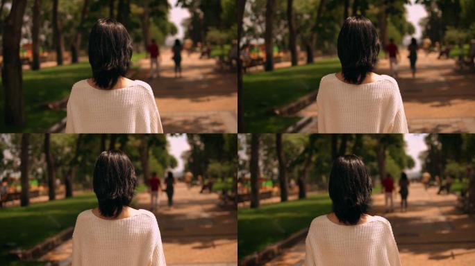 一名女子在公园散步的后视图
