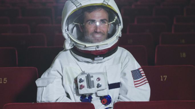一名宇航员一边吃爆米花一边看电影。