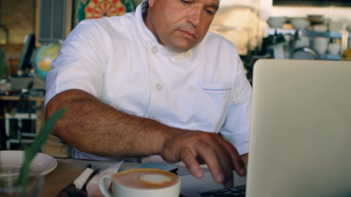 厨师在柜台用笔记本电脑工作