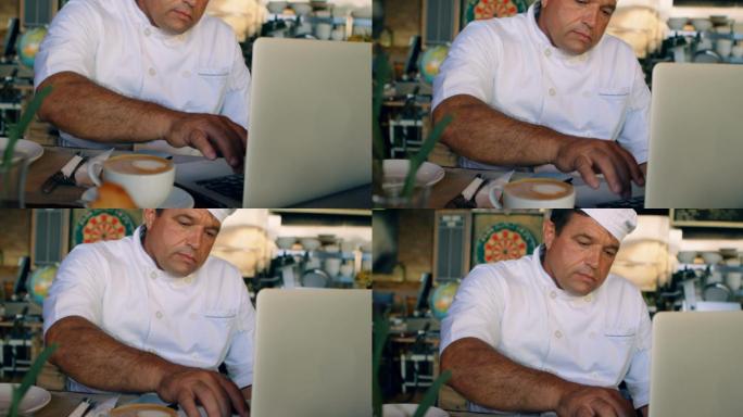 厨师在柜台用笔记本电脑工作