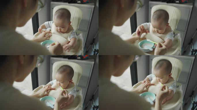 母亲用汤匙喂小男孩