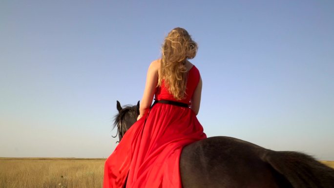 骑着红色长裙的骑马女孩在乡村公路上骑马