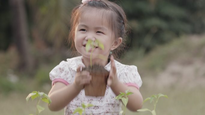 小女孩拿着盆里的幼苗