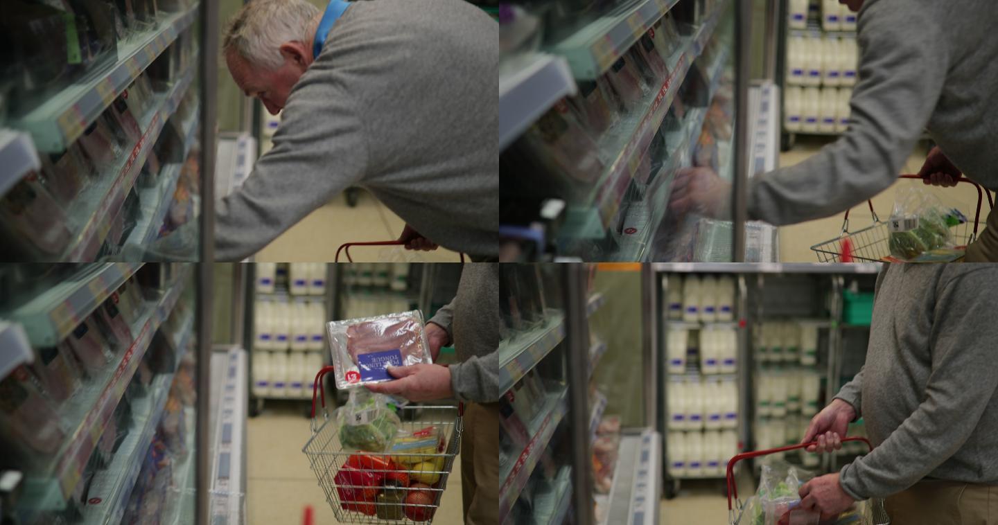 老人在超市里捡起一包火腿放进篮子里。