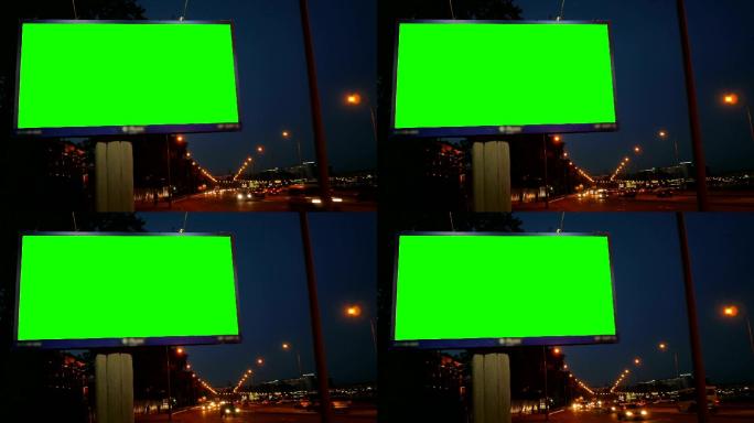繁忙的夜间街道上的绿色屏幕广告牌