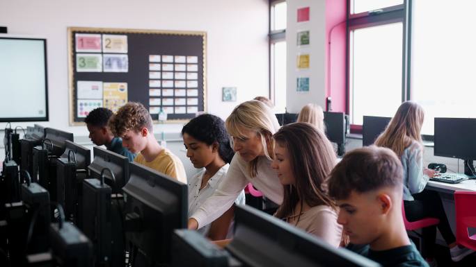 女教师帮助高中女生在计算机课上学习