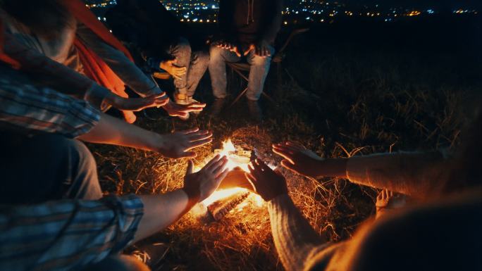 朋友们坐在篝火旁暖手