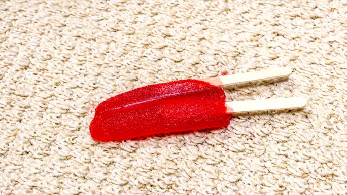红色冰棒在地毯上融化